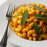 Single serving of butternut squash mac and cheese plated elegantly with herbs