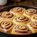 Cottage cheese cinnamon rolls with glaze in baking pan showing golden spiral texture