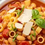 Pasta fagioli in white bowl with ditalini pasta, beans, and Parmesan cheese