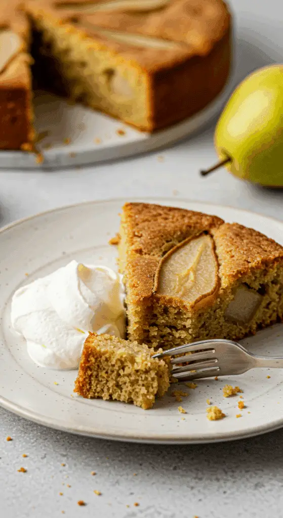 Pear olive oil cake slice on plate with whipped cream showing moist texture